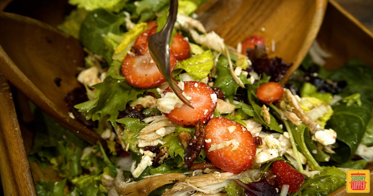 Mixing strawberry chicken salad in a bowl up close