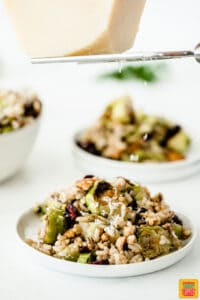 Shaving cheese over roasted brussels sprouts wild rice salad