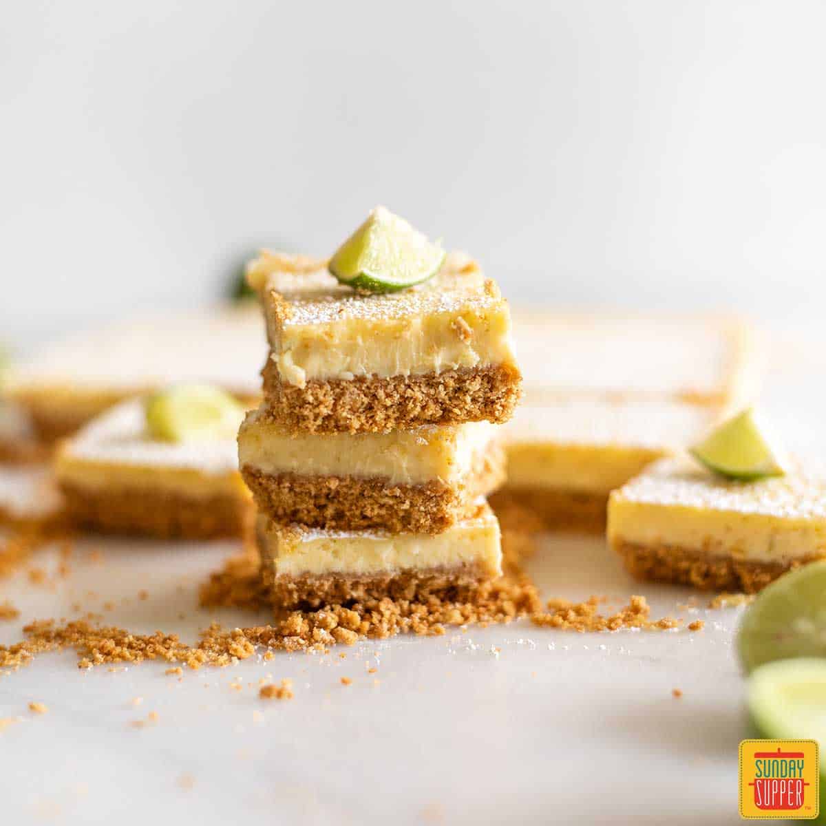 A stack of three key lime pie bars next to the remaining pie squares