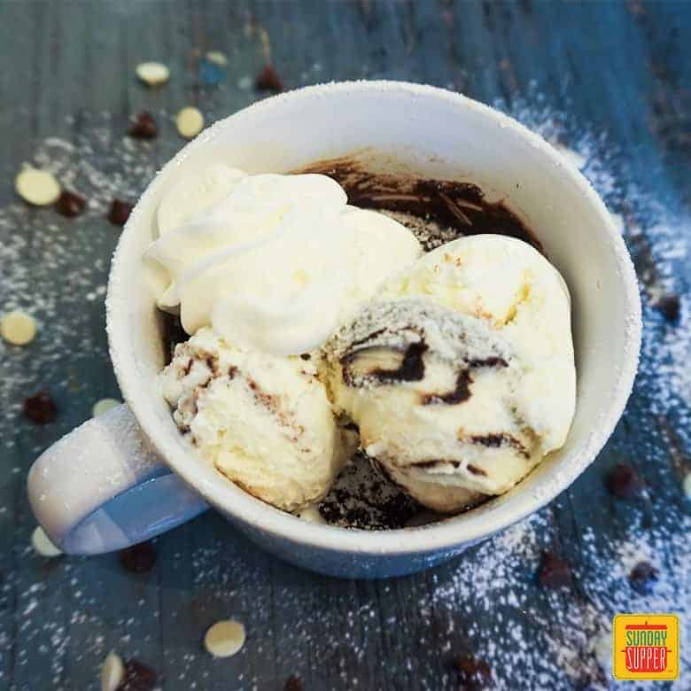 Brownie in a mug topped with ice cream and whipped cream