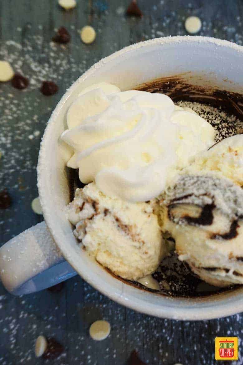 Brownie mug cake in a white mug with whipped cream and ice cream on top