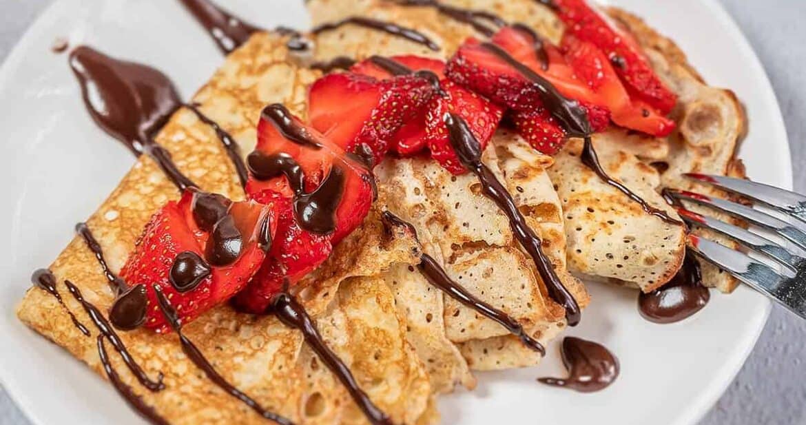 Strawberry crepes on a white plate with chocolate sauce