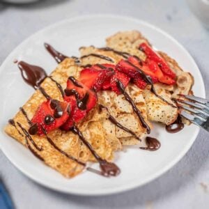 Strawberry crepes on a white plate with chocolate sauce