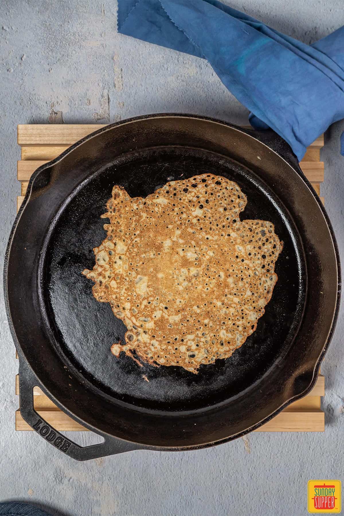 Crepes cooking in a black skillet