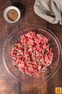 combining spices and ground beef in a bowl