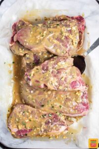 Uncooked lamb chops covered with the garlic mustard rosemary lamb marinade
