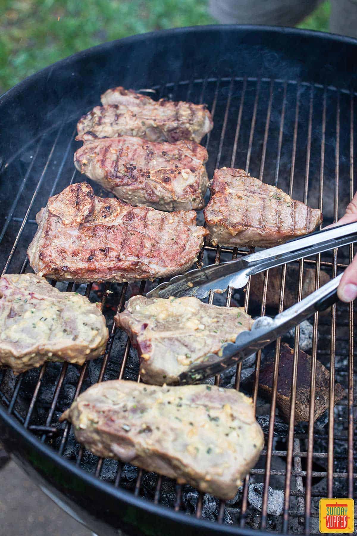 Flipping the lamb chops on the grill to cook for grilled lamb chops