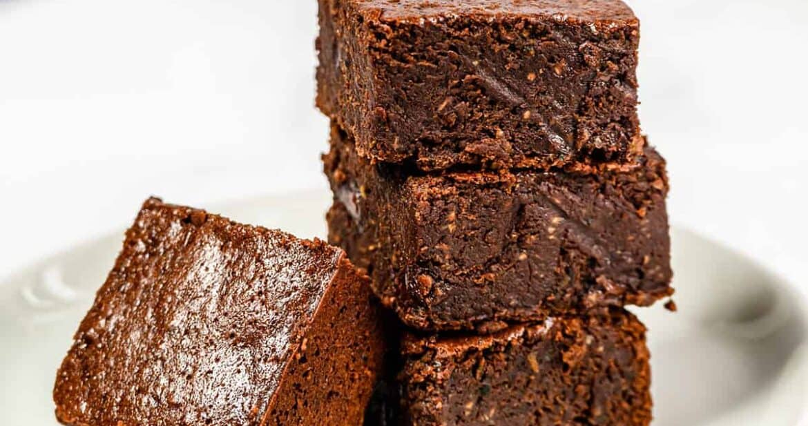 Four zucchini brownies with coconut oil on a plate