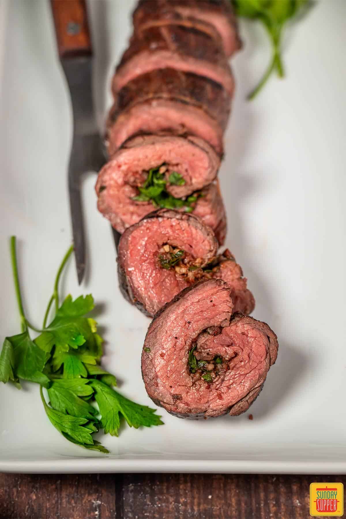 Sliced beef roulade on a white platter
