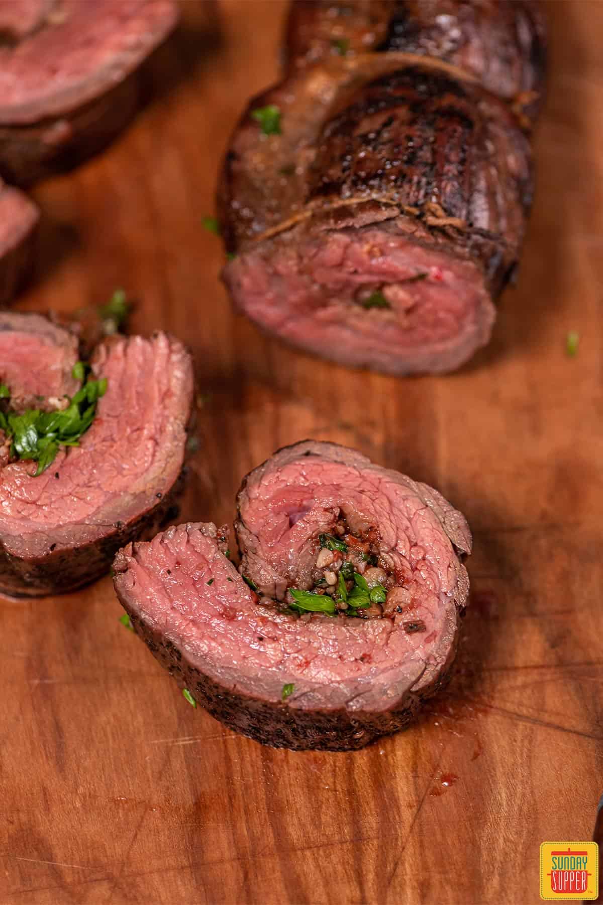 Sliced beef roulade on a wooden surface