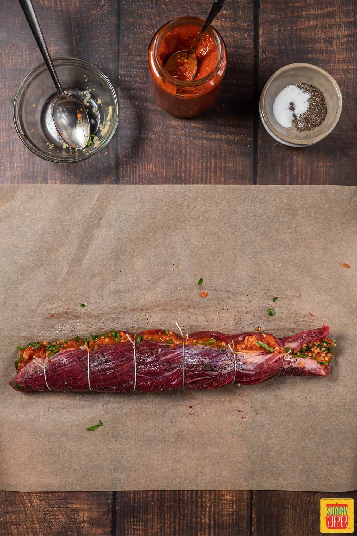 Harissa beef roulade recipe rolled on paper and tied with twine