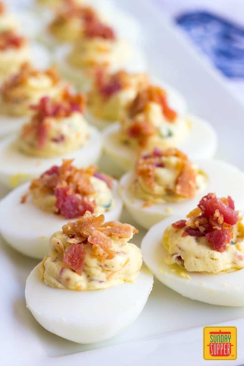 Two rows of jalapeno popper deviled eggs topped with bacon