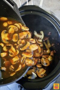 Adding the cooked mushrooms to the slow cooker