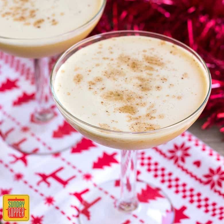 Bourbon flip cocktail in a wide cocktail glass with a winter-theme towel underneath