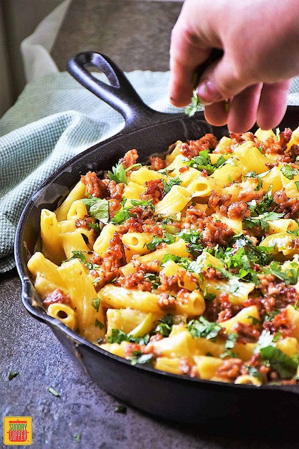 Baked ziti with sausage and peppers in a black cast iron skillet