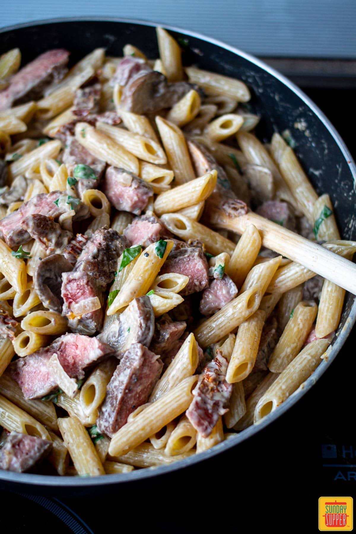 Creamy penne pasta with sliced prime rib in a pot