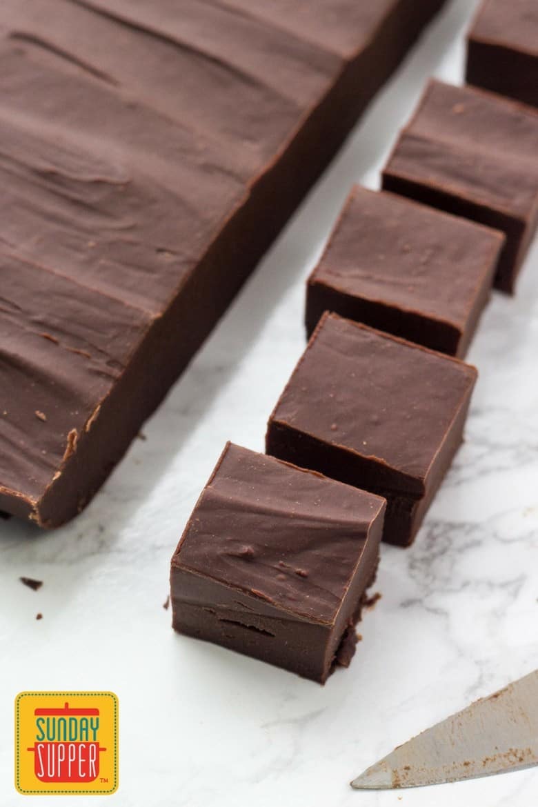 Slices of baileys fudge on a white marble surface with the knife to the side