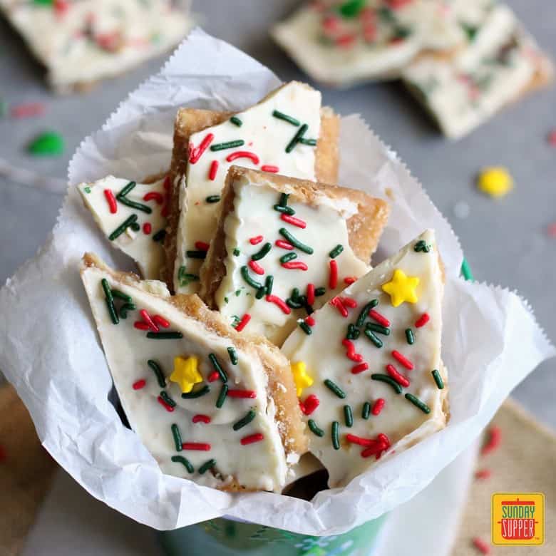 white chocolate christmas crack in white gift paper in a christmas-themed tin