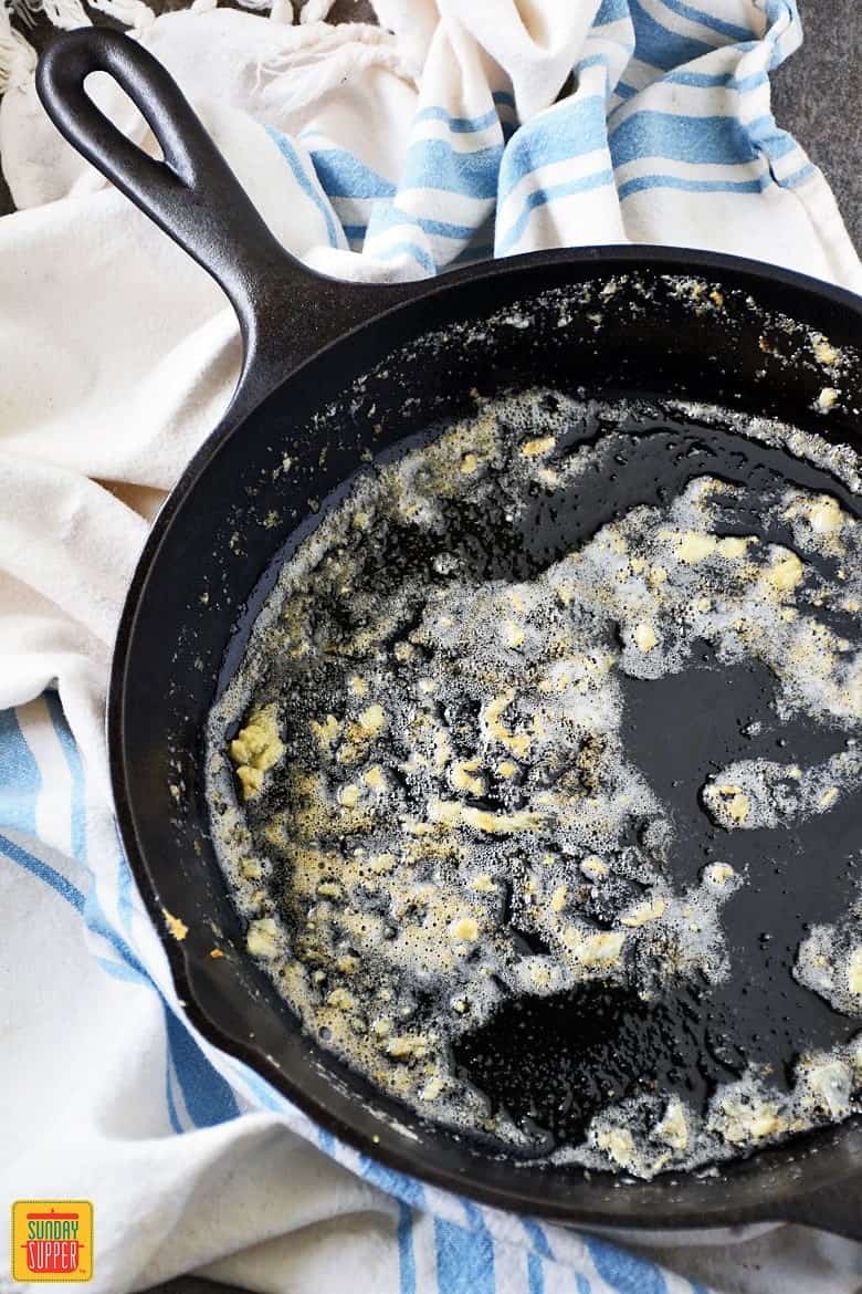 Cooking garlic and butter in a cast iron skillet for gluten-free potatoes au gratin