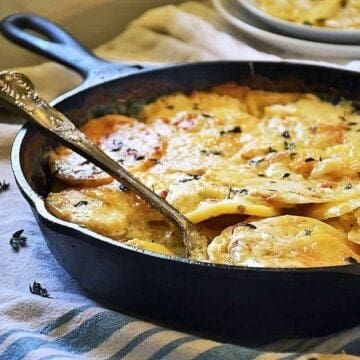 Gluten free au gratin potatoes in a skillet on a towel