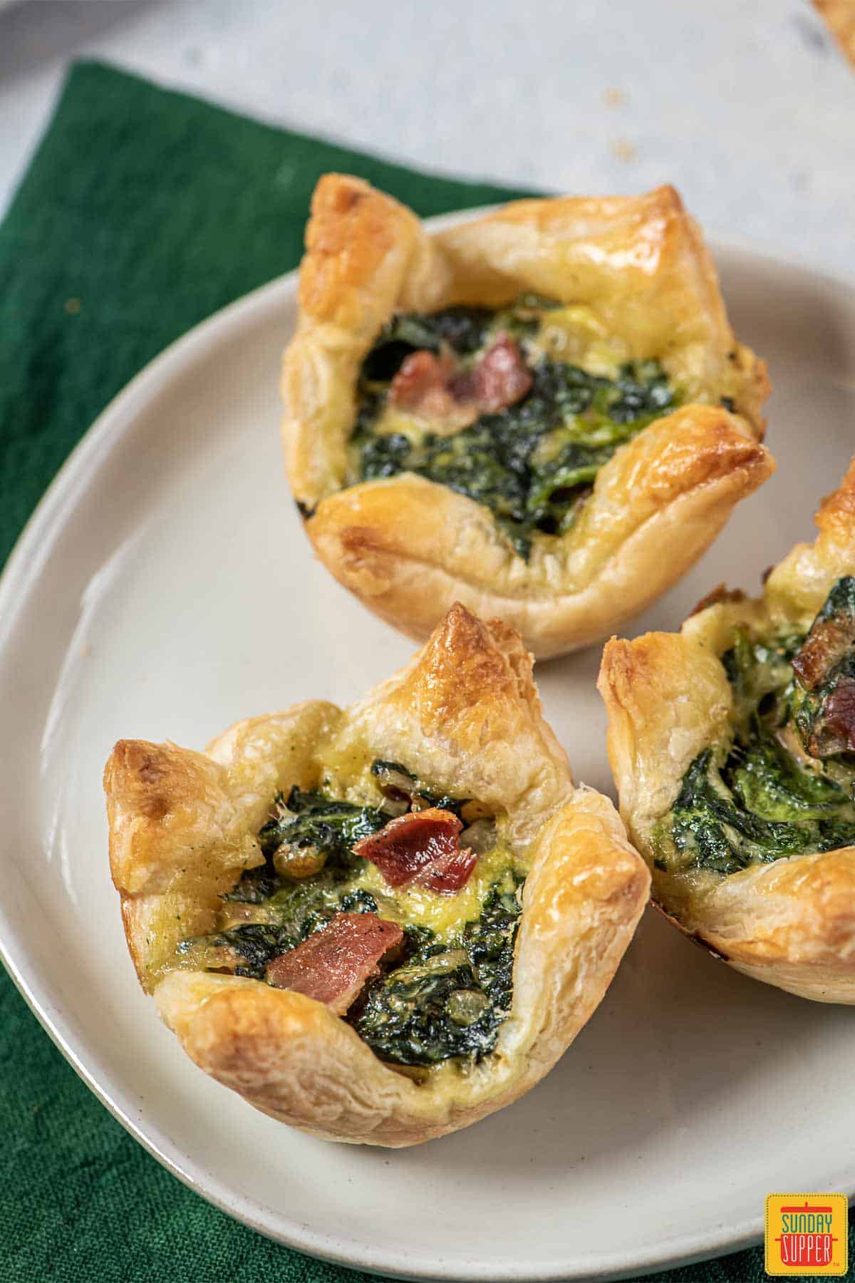 three spinach puff pastries on a white plate