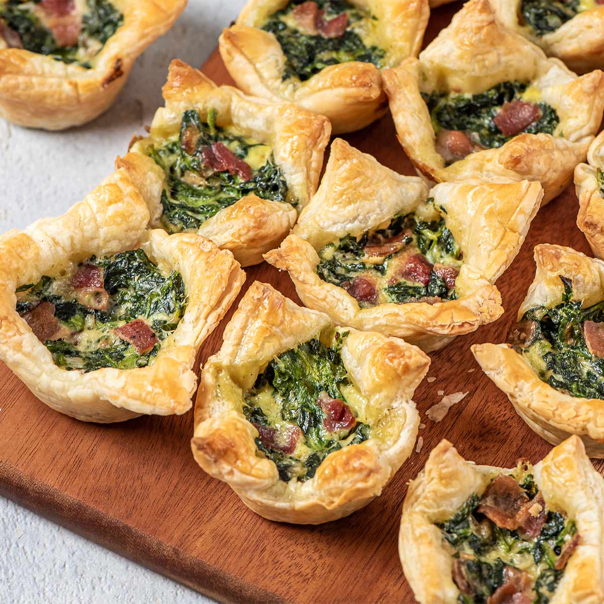 rows of spinach puff pastries on a serving board