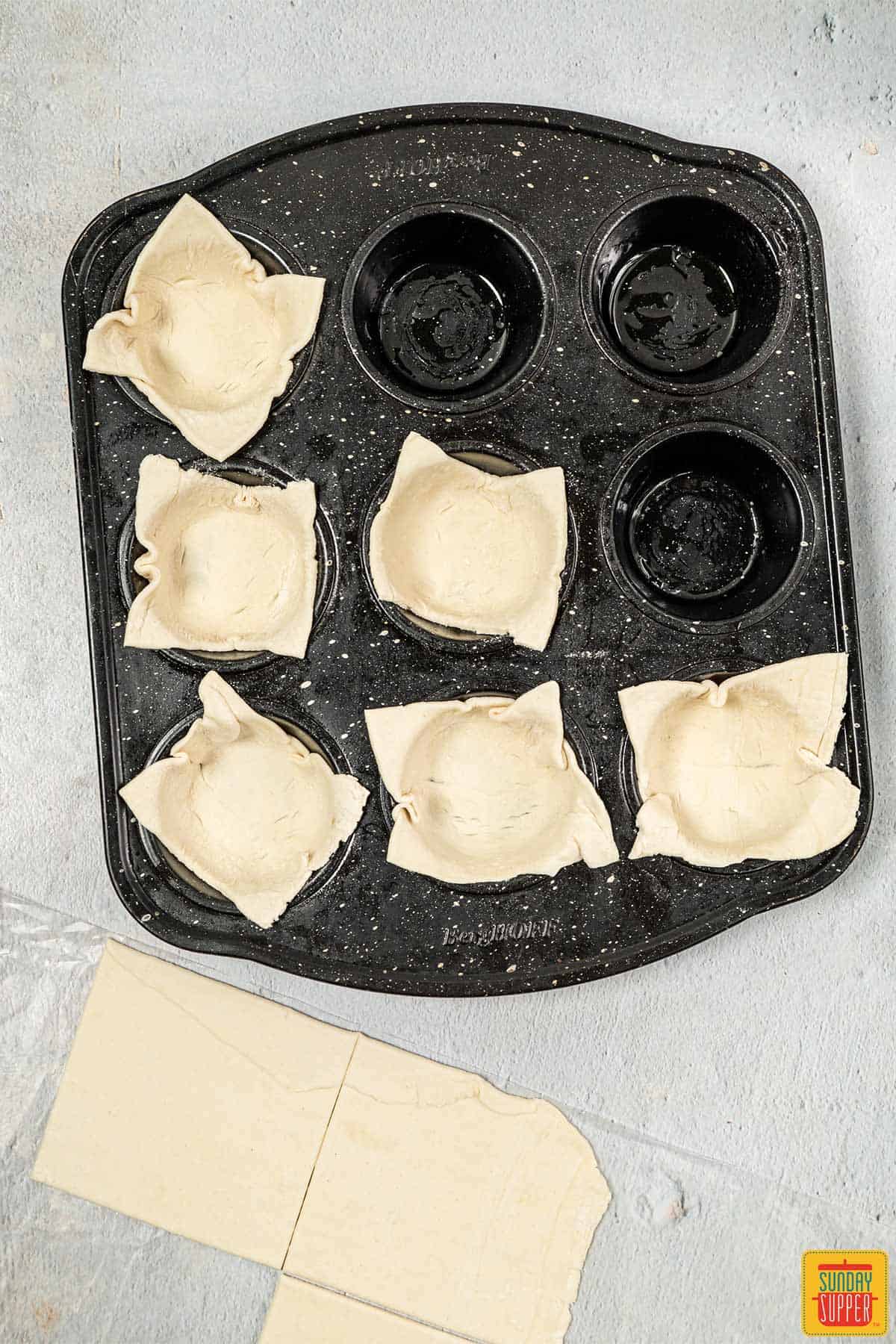 adding puff pastry to muffin tin