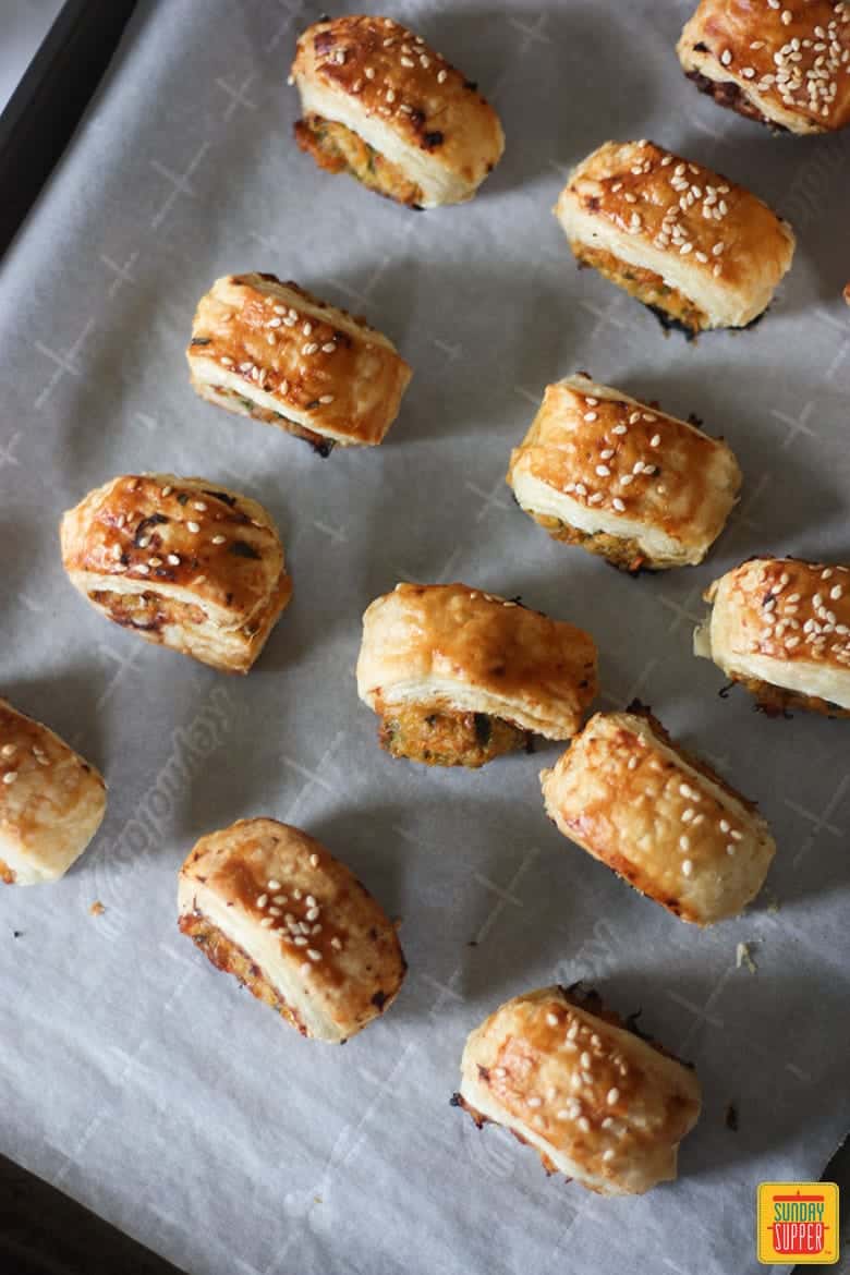 Rows of sausage rolls on a baking sheet