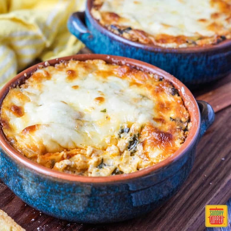 Chorizo Cheese Dip with Spinach in blue shallow bowls with handles