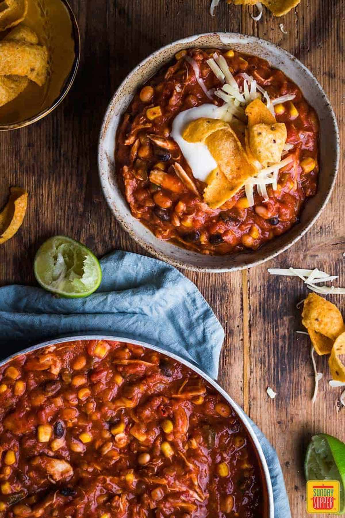 A bowl of chicken chili next to the skillet of chili - make ahead freezer meals