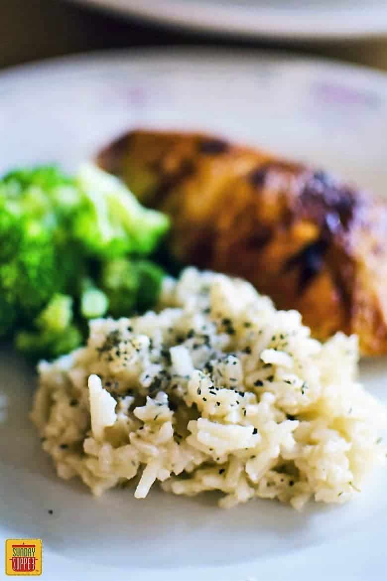 Homemade Rice-A-Roni on a plate to the side of chicken and broccoli