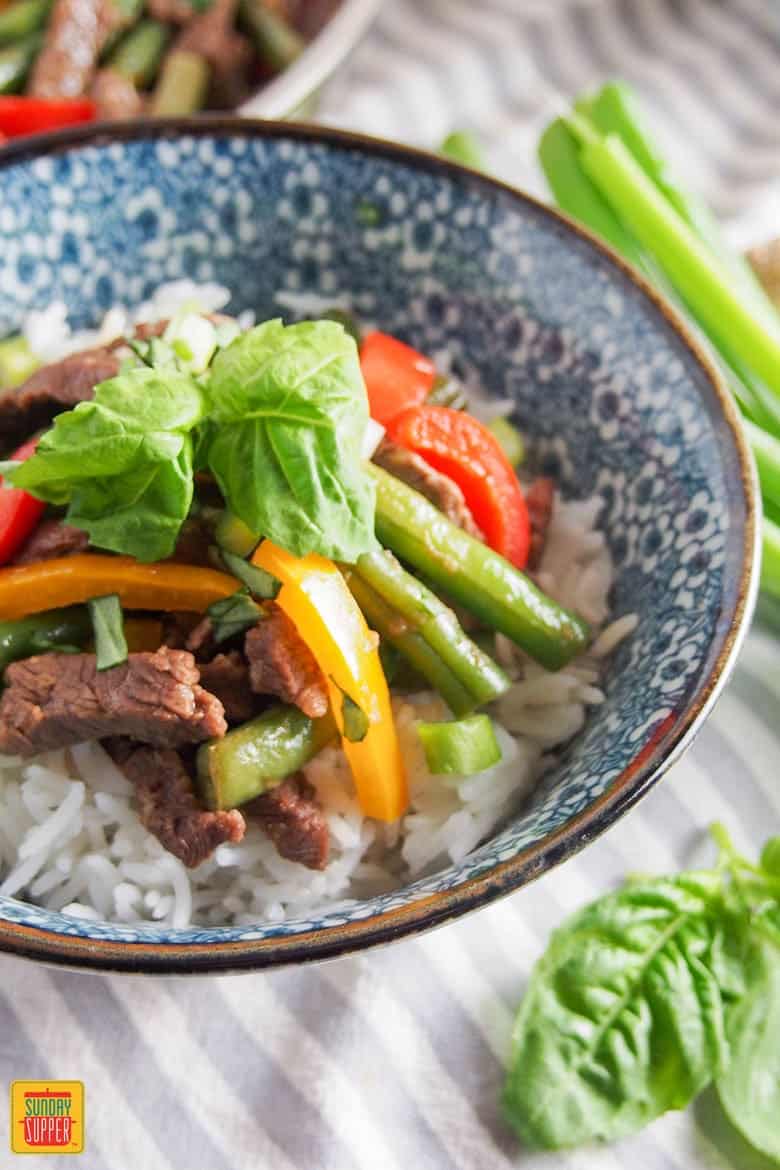 Asian beef stir fry recipe in a blue and white bowl with green beans