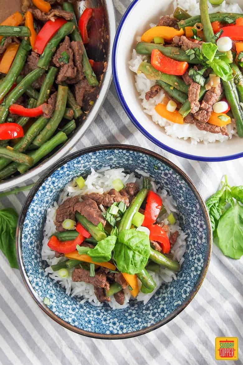 Asian beef stir fry recipe in two bowls next to the skillet