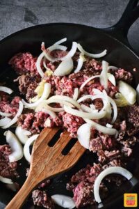 Adding onions to ground beef in skillet