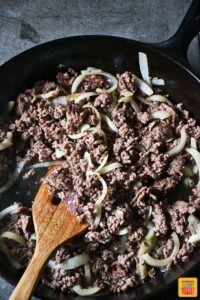 Browned ground beef and softened onions in a skillet for ground beef stroganoff