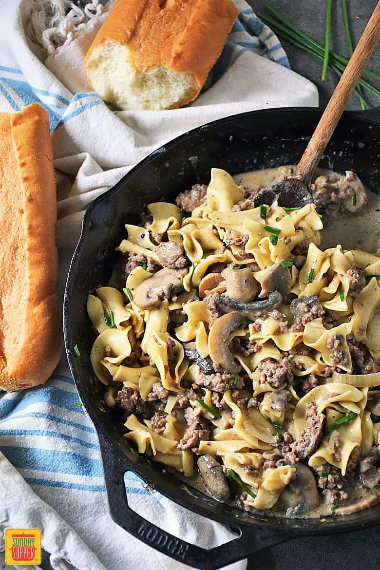 Hamburger stroganoff in a skillet with a side of fresh bread