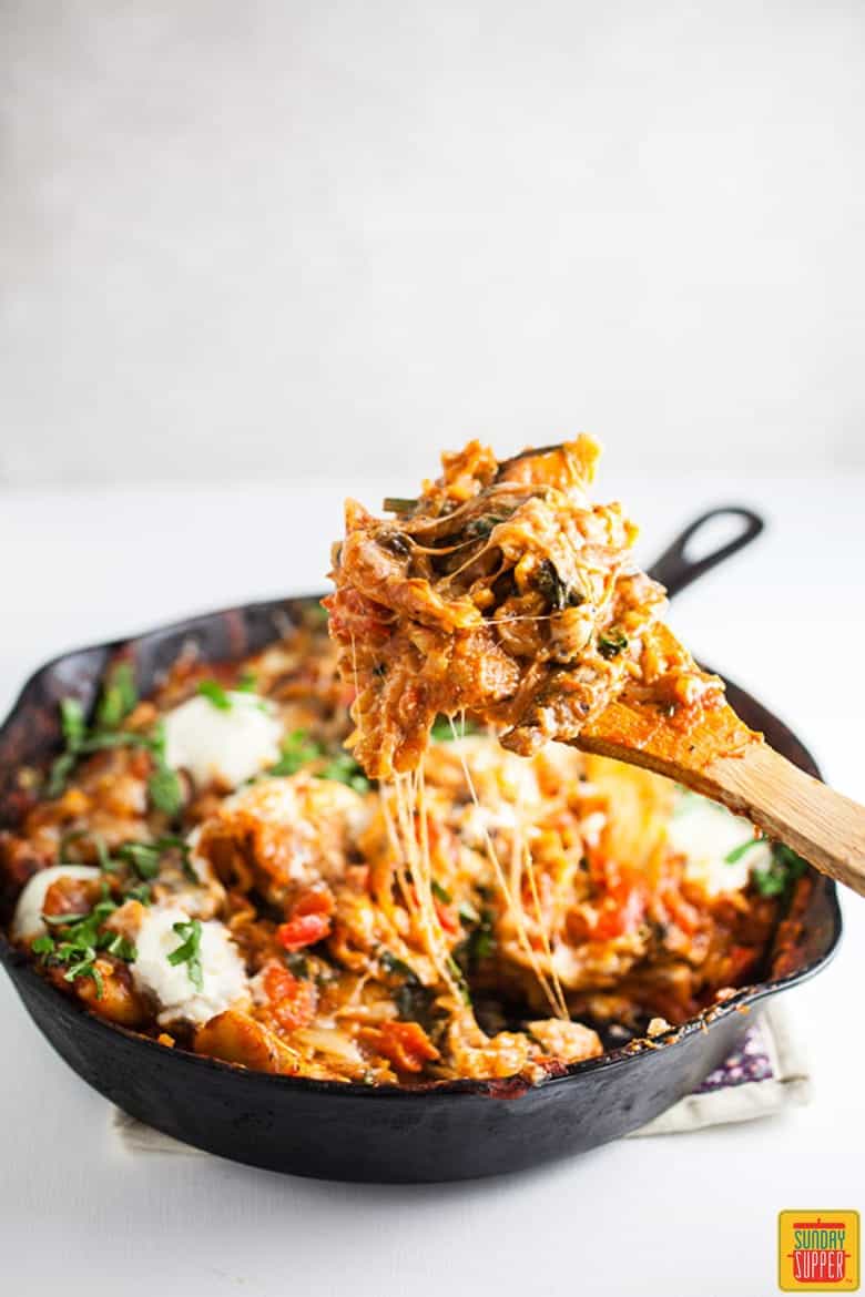 Vegetarian skillet lasagna in the skillet with a wooden spoon