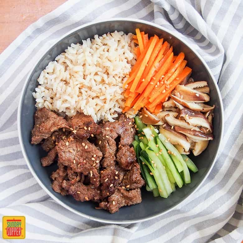 beef bulgogi meal prep bowl set on a striped blue table cover