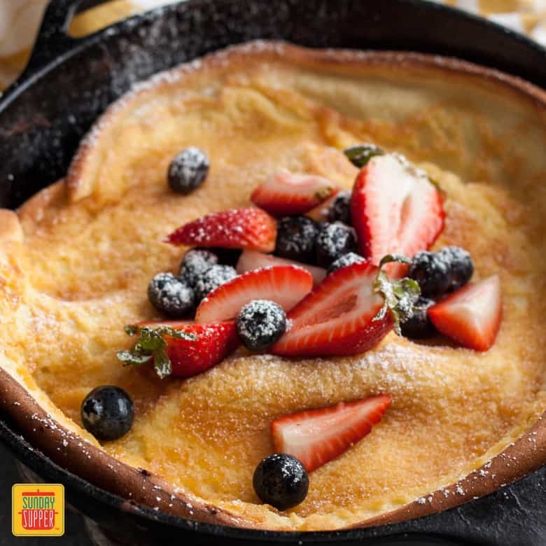 Berries and Cream Dutch Baby in a skillet with powdered sugar