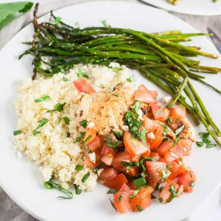 Grilled Bruschetta Chicken Breasts on white plate with asparagus and couscous