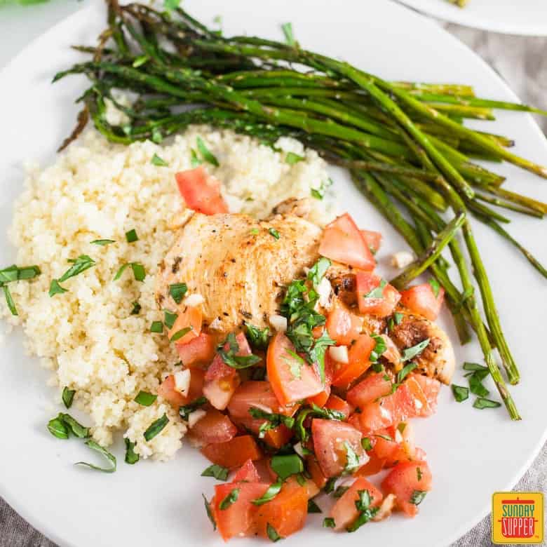 Grilled bruschetta chicken breasts with couscous and grilled asparagus on a plate