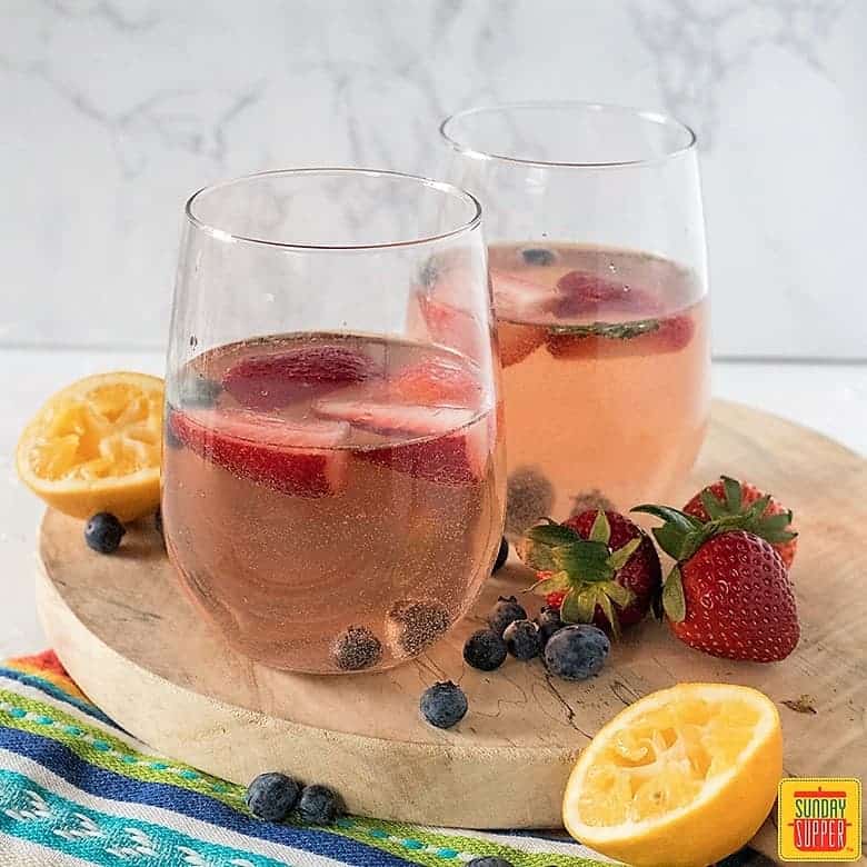 two glasses of rose sangria on a rustic round board