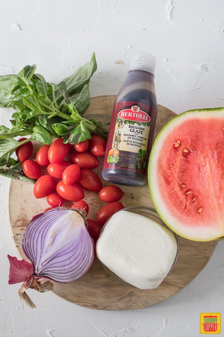 watermelon basil salad ingredients on a rustic round board