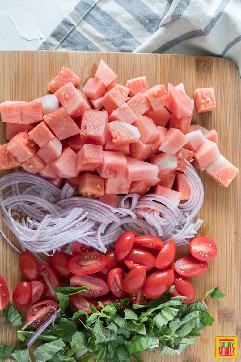 watermelon basil salad ingredients diced on a wooden board