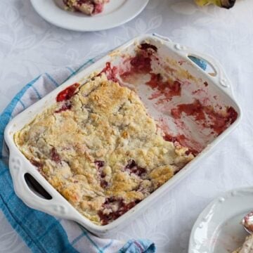 Strawberry Banana Dump Cake in a baking dish on a table, served in plates. Delicious and easy fruit dessert