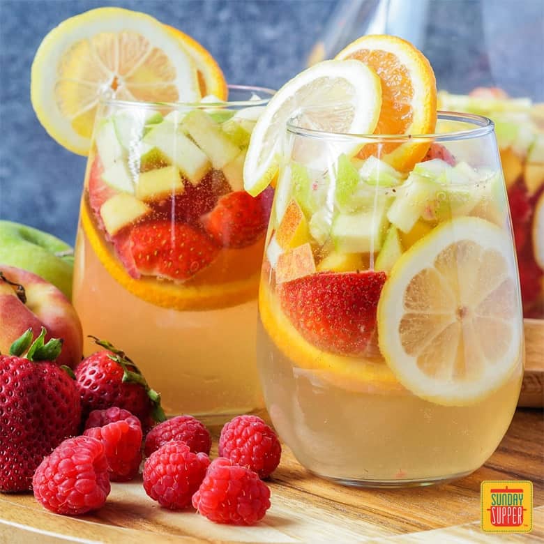 Moscato Sangria in a glass with fresh strawberries, raspberries, apples, peaches, oranges, and lemons