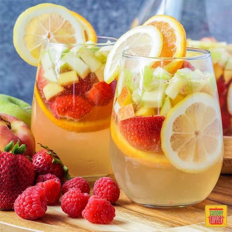 Moscato Sangria in two glasses with fresh fruit and citrus on the lip of each glass