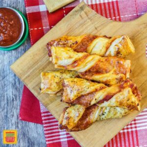 Pizza Twists on a wooden board with marinara sauce on the side