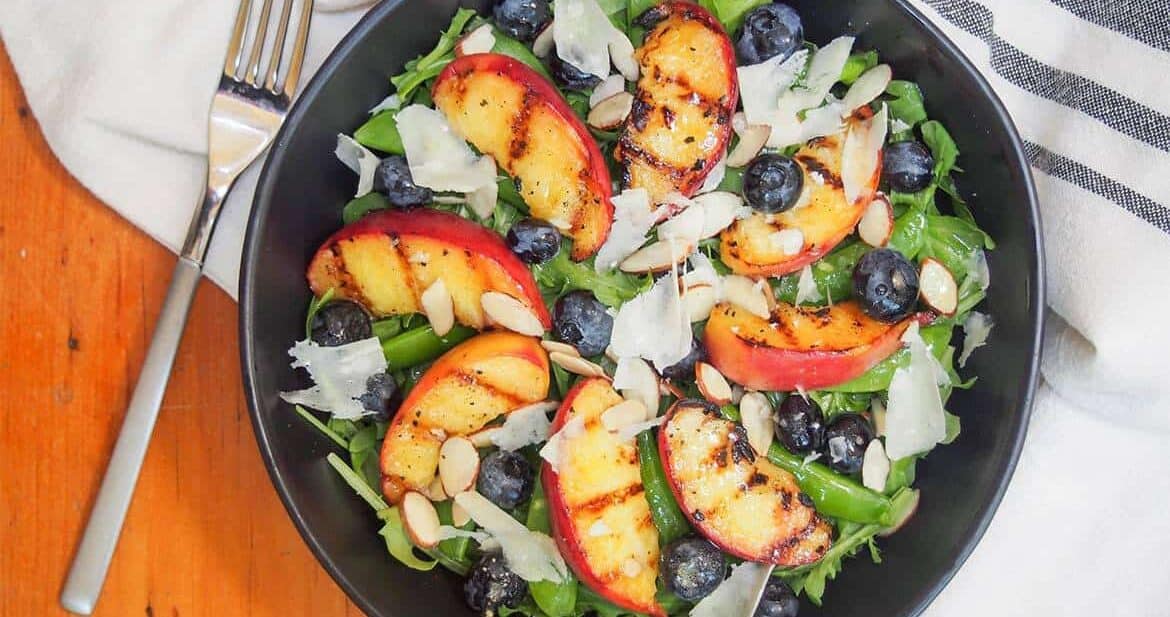 grilled peaches salad in a black bowl