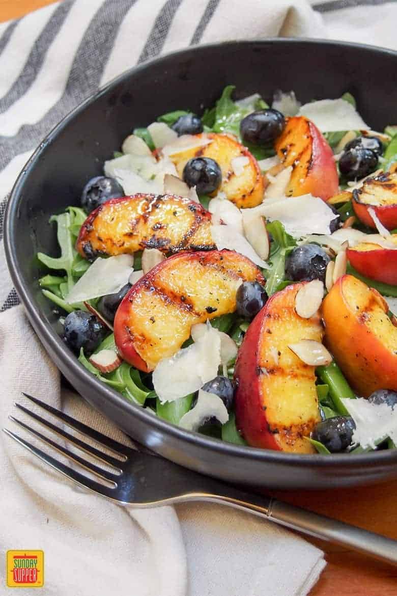 grilled peaches salad in a black bowl with fresh grilled peaches